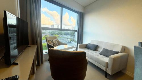 a living room with a white couch and a window at Parque do Cais - Flats Premium no Recife por Yolo in Recife
