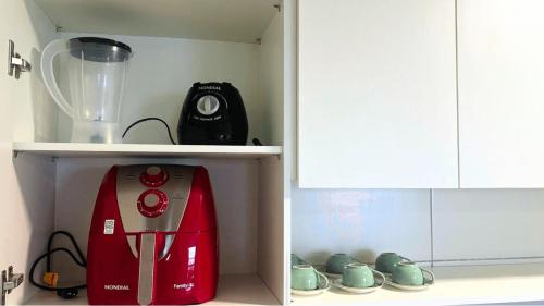 a kitchen cabinet with a red blender and cups at Parque do Cais - Flats Premium no Recife por Yolo in Recife