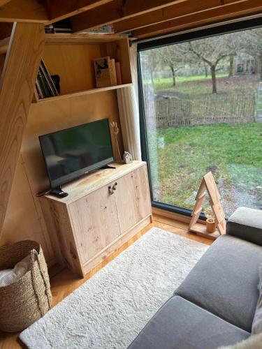a living room with a tv and a large window at L'arche De Noé in Dinant