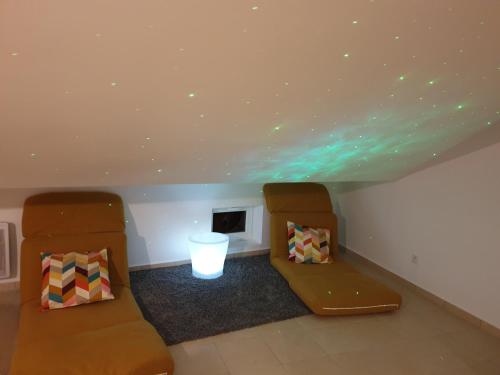 - deux chaises dans une chambre avec des lumières vertes au plafond dans l'établissement A04 Le Lounge - Clim- Wifi - Coeur de Ville, à Béziers