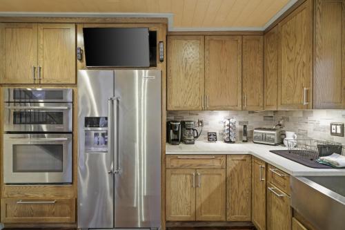 a kitchen with wooden cabinets and a stainless steel refrigerator at Luxurious Poconos Retreat - Hot Tub, Sauna, Games in East Stroudsburg