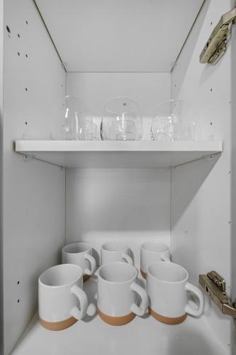 a row of white cups sitting on a shelf at Modern Apt W Pool, Gym & Free "p"prime Location in Rogers