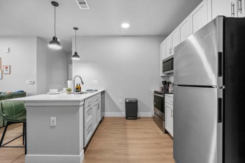 a kitchen with a stainless steel refrigerator in it at Modern Apt W Pool, Gym & Free "p"prime Location in Rogers