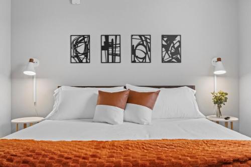 a bedroom with a white bed with orange and white pillows at Modern Apt W Pool, Gym & Free "p"prime Location in Rogers