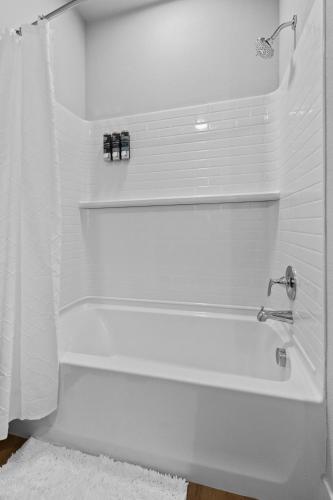 a white bathroom with a bath tub with a shower curtain at Modern Apt W Pool, Gym & Free "p"prime Location in Rogers
