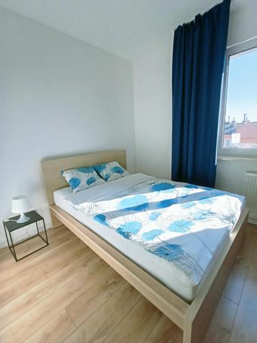 a bedroom with a bed with a blue curtain and a window at Lux Corner Park przestronne mieszkanie z klimatyzacją, balkonem i podziemnym garażem in Pruszków