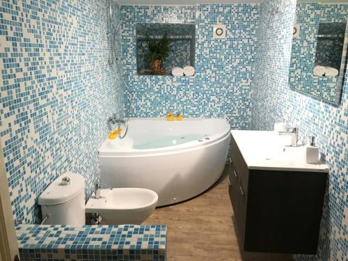baño de azulejos azules con bañera y aseo en La Tana Dei Leoni Affittacamere, en Florencia