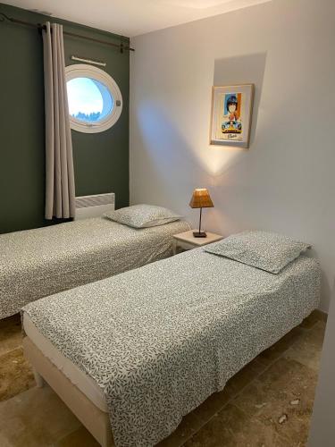 deux lits dans une chambre avec une fenêtre dans l'établissement Au pied des Alpilles, à Paradou