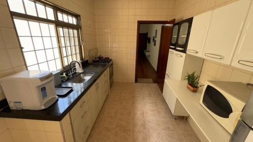 a large kitchen with a sink and a microwave at Casa de Temporada Umuarama in Uberlândia