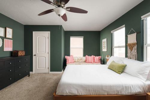 a bedroom with green walls and a bed with a ceiling fan at Victorian Retreat in Barrio Logan 1mi to Downtown in San Diego