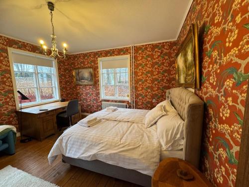 a bedroom with red wallpaper and a bed and a desk at Hishult No 5 Hishults Prästgård in Hishult