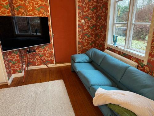 a living room with a blue couch and a flat screen tv at Hishult No 5 Hishults Prästgård in Hishult