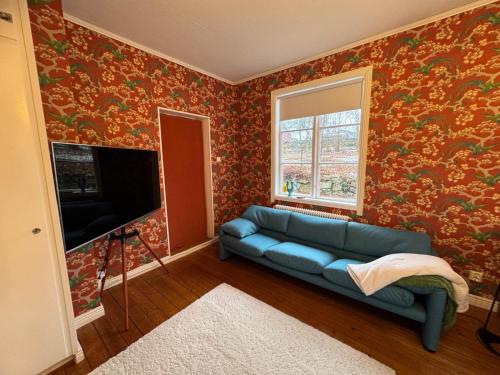 a living room with a blue couch and a tv at Hishult No 5 Hishults Prästgård in Hishult
