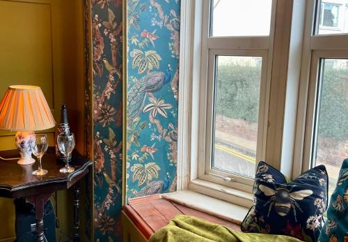 a room with a window with a chair and a lamp at Cheviot House Gallery And Guest Rooms in Wooler