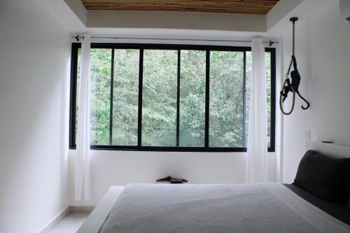 a bedroom with a large window with white curtains at Nosara Verde in Nicoya