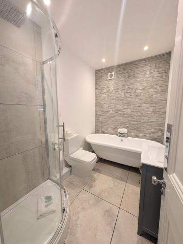 a bathroom with a tub and a toilet and a shower at South Coast Seaside Holiday Home -3 BED-GF-Sleeps 8-Free Parking-Walk to Beach-Private Garden- Families-Professional Groups-Contractors WELCOME in Bournemouth