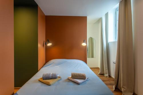 une chambre avec un lit avec deux oreillers dessus dans l'établissement Le Jules Verne - Cour et Parking privé, à Amiens