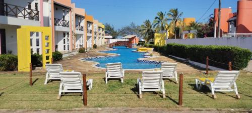 a group of chairs in front of a swimming pool at Casa de praia in Maxaranguape