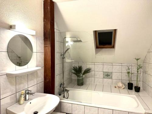 une salle de bain avec un lavabo, une baignoire et un miroir dans l'établissement On 22nd, à Colmar
