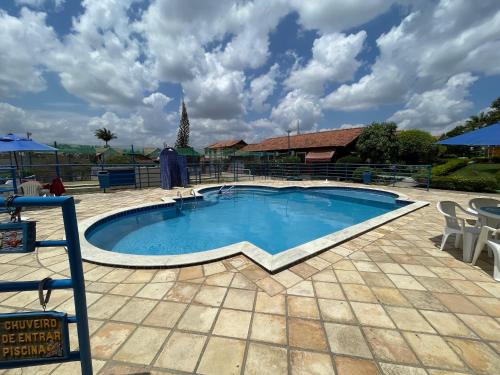 a large swimming pool with a patio and chairs around it at Aconchego em Gravatá! Temporada in Gravatá