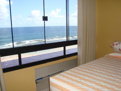 a bedroom with a view of the ocean and a bed at Farol Barra Flat 202 in Salvador
