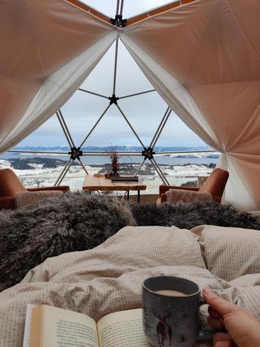 a person reading a book in a tent with a cup of coffee at Forbord Dome in Tilleraune