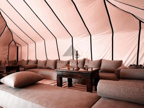 a room with a couch and a table in a tent at Merzouga Luxurious Sahara Camps in Merzouga