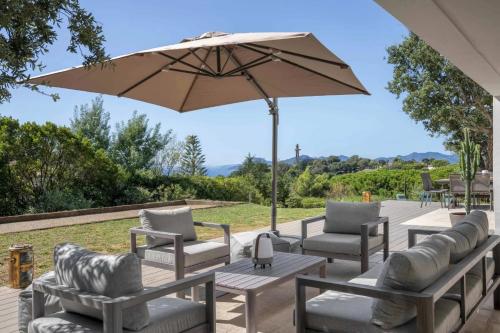 un patio avec des chaises et une table avec un parasol dans l'établissement Beautiful 5 bedroom villa with sea view & pool, à Vallauris