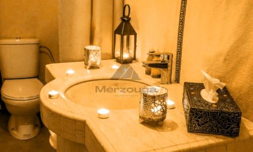 a bathroom with a tub with a toilet and candles at Merzouga Luxurious Sahara Camps in Merzouga