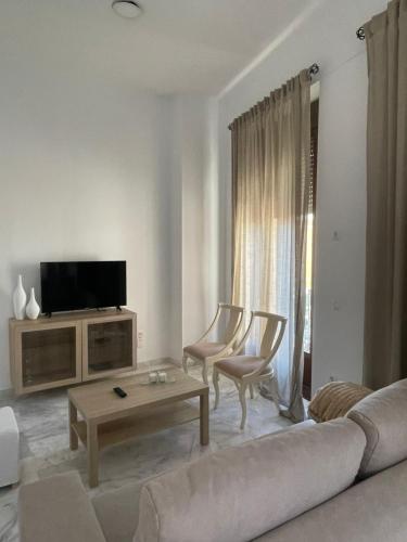 Una sala de estar con un sofá y sillas y un televisor. en Apartamentos La Bola 94, en Ronda