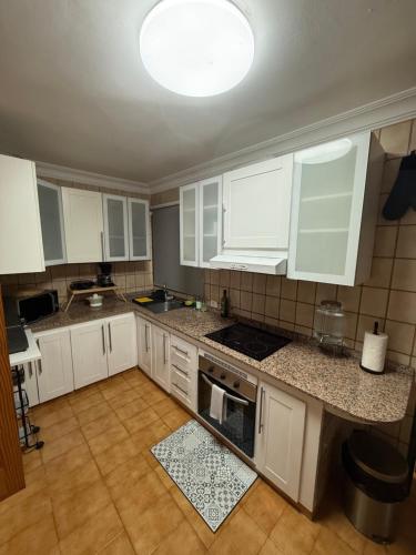 Una cocina con gabinetes blancos y encimera. en Casa Tamarán, en Arguineguín