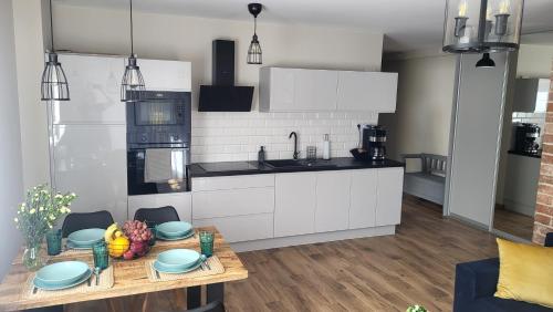 una cocina con armarios blancos y una mesa con fruta. en Loftowe Zacisze nad Bałtykiem - 5 to the Sea, en Międzywodzie