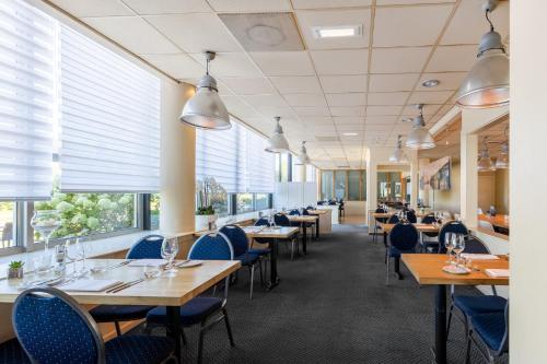 a dining room with tables and chairs and windows at Garner Hotel Maastricht by IHG in Maastricht