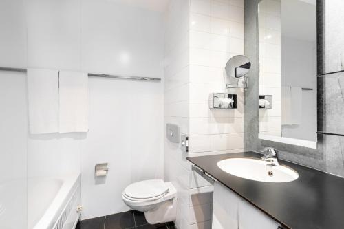 a white bathroom with a sink and a toilet at Garner Hotel Maastricht by IHG in Maastricht