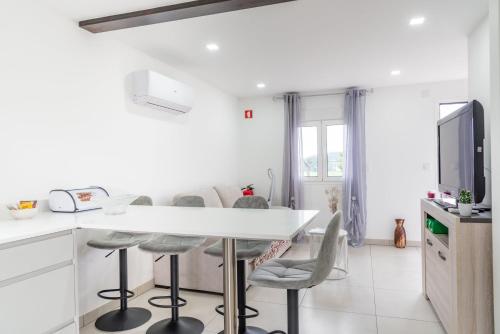 a white kitchen with a white table and chairs at Casa do rochio in Mucelão