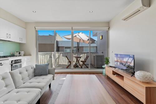 a living room with a couch and a flat screen tv at Stylish North Melbourne Stay, Minutes to CBD in Melbourne