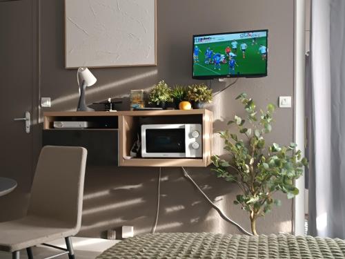 un salon avec une télévision sur un mur dans l'établissement STUDIO CALME PROCHE CENTRE BORDEAUX, à Bordeaux