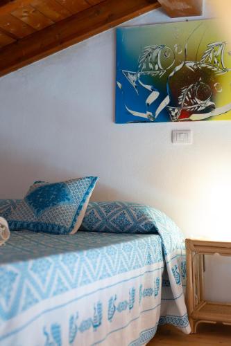 a bedroom with a bed with a painting on the wall at Residence Fior di Sulcis in Calasetta