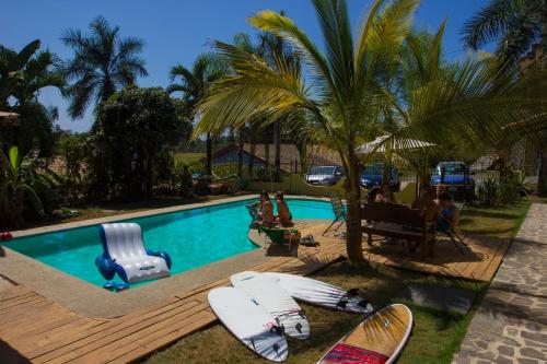 a group of people sitting around a swimming pool with surfboards at Wipeout Hostel in Jacó