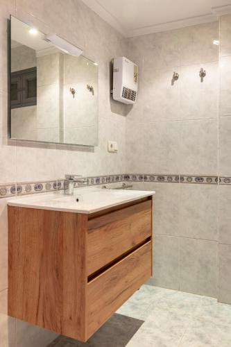 a bathroom with a sink and a mirror at Apartamentos Asturias Holidays by Gestión House in Noreña
