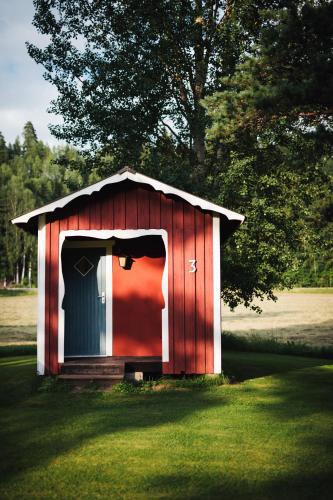 a red shed with a door in the grass at Björkebo Camping in Stöllet