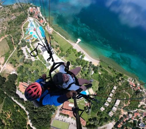 a person in a helmet on a parachute over the ocean at Blue Lake hostel in Ohrid