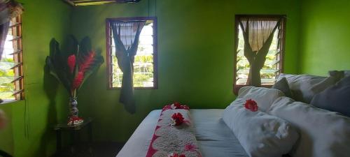 a green room with a bed with red flowers on it at Jima's Home Retreat in Matei
