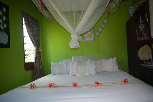 a green bedroom with a white bed with flowers on it at Jima's Home Retreat in Matei