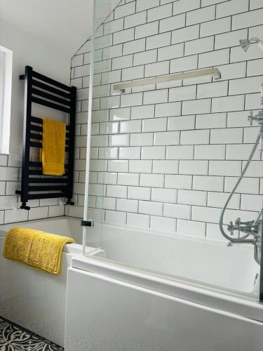 a white bathroom with a tub and a yellow towel at Seascape Luxury sea front apartment in Bangor