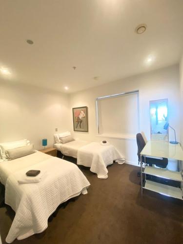 a room with two beds and a table and a window at Knights' Retreat Napier in Napier