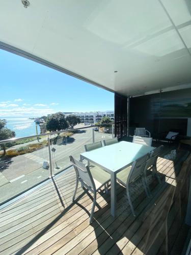 a table and chairs on a balcony with a view of the ocean at Knights' Retreat Napier in Napier
