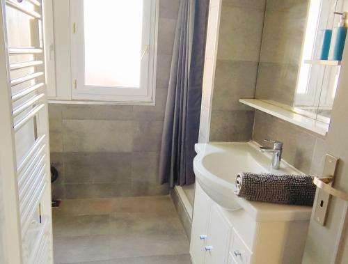 une salle de bain blanche avec un lavabo et une fenêtre dans l'établissement 3 chambres 100m plage, à Berck-sur-Mer