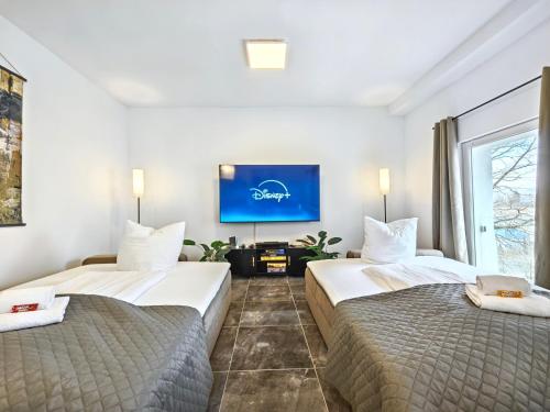 two beds in a hotel room with a flat screen tv at Designer Loft für bis zu 15, Whirlpool, Infrarotsauna, Billard, Pokertisch, 2 Bäder in Nürnberg