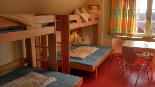 Zimmer mit Etagenbett, 2 Etagenbetten und einem Tisch in der Unterkunft Jugendherberge Otterndorf in Otterndorf